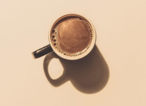 Overhead view of a cup of coffee with a shadow of the mug.
